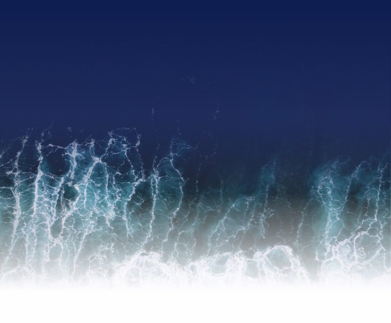 Aufsicht auf eine Welle im Meer die sich am Strand bricht
