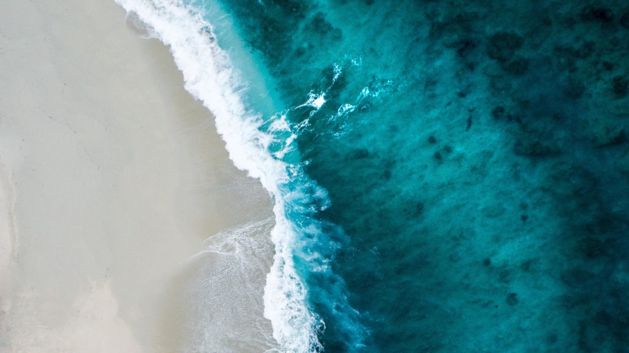 Big waves with spray roll onto the beach
