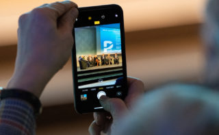 Picture of a smartphone with a recording of the panel discussion on stage at the opening event of the DAM