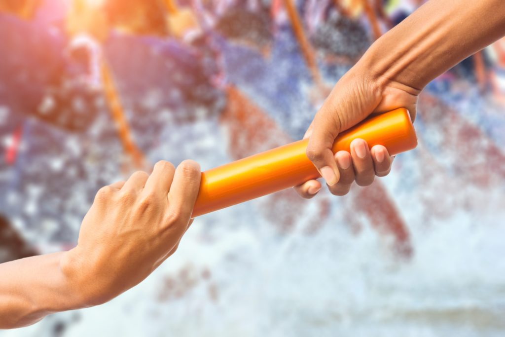 Hands passing relay baton on rowing.