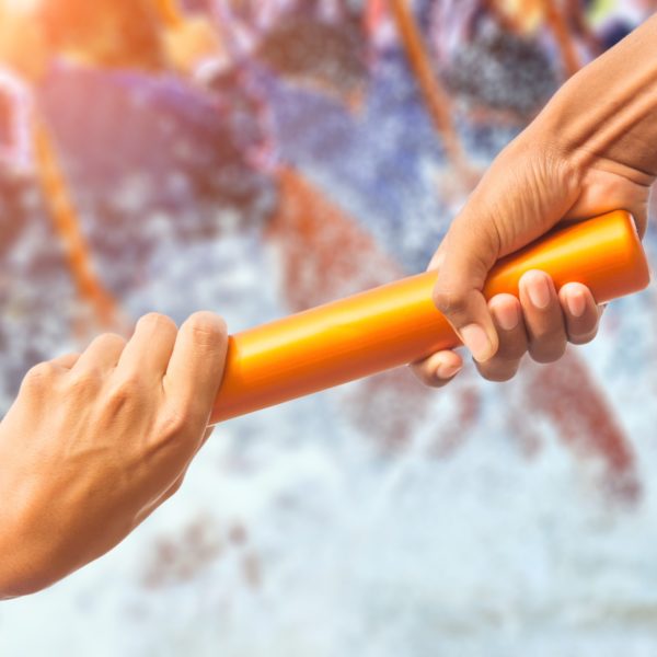 Hands passing relay baton on rowing.