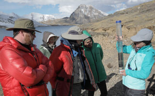 Bron­wen Ko­ne­cky von der Wa­shing­ton Uni­ver­si­ty in St. Lou­is (ganz rechts) un­ter­sucht ei­nen Kern von See­se­di­men­ten aus dem Si­bi­n­a­co­cha-See in Peru.