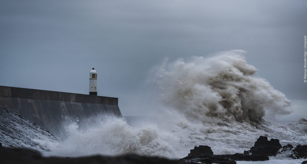 Eine Welle schlägt mit Wucht gegen einen Wellenbrecher