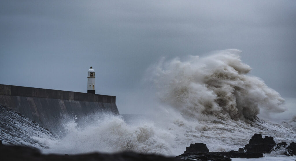 Eine Welle schlägt mit Wucht gegen einen Wellenbrecher