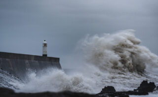 Eine Welle schlägt mit Wucht gegen einen Wellenbrecher