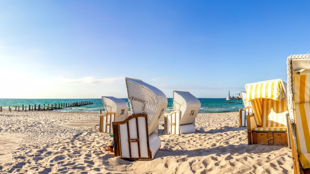 Strandkörbe im Sand am Strand unter strahlend blauem Himmel