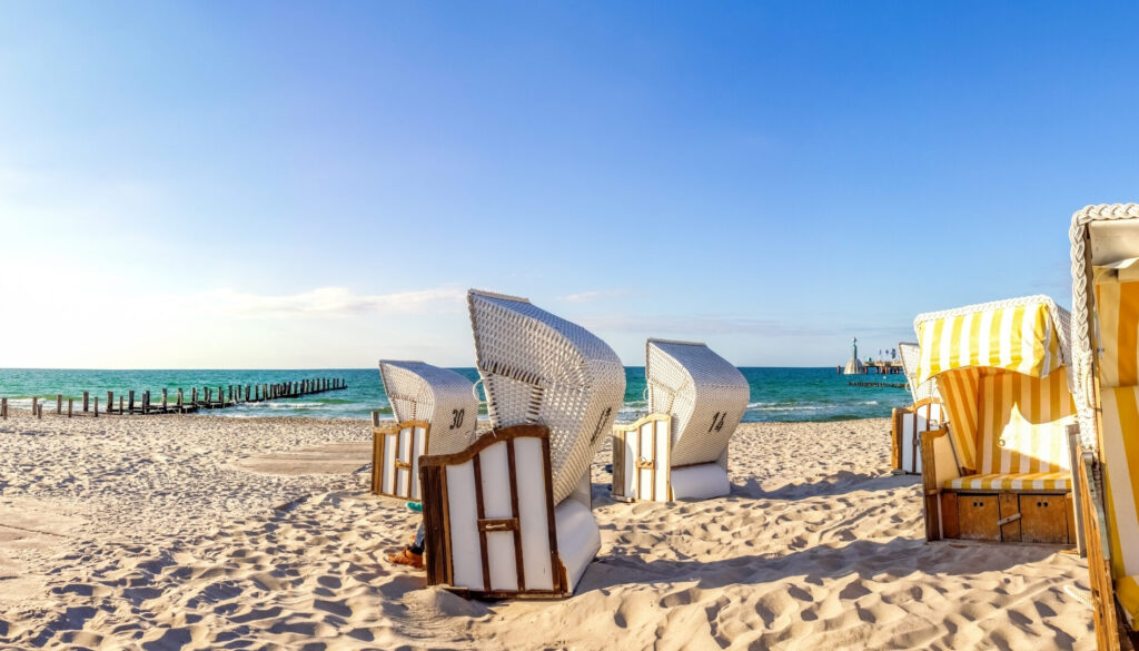 Strandkörbe im Sand am Strand unter strahlend blauem Himmel